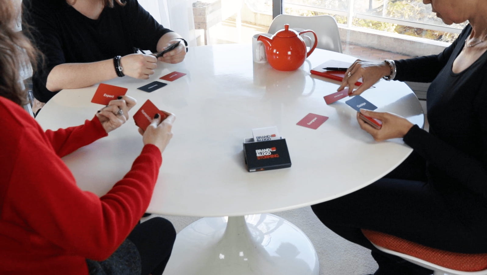 Séance de brand storming autour d'une table, les participants manipulent les cartes du jeu